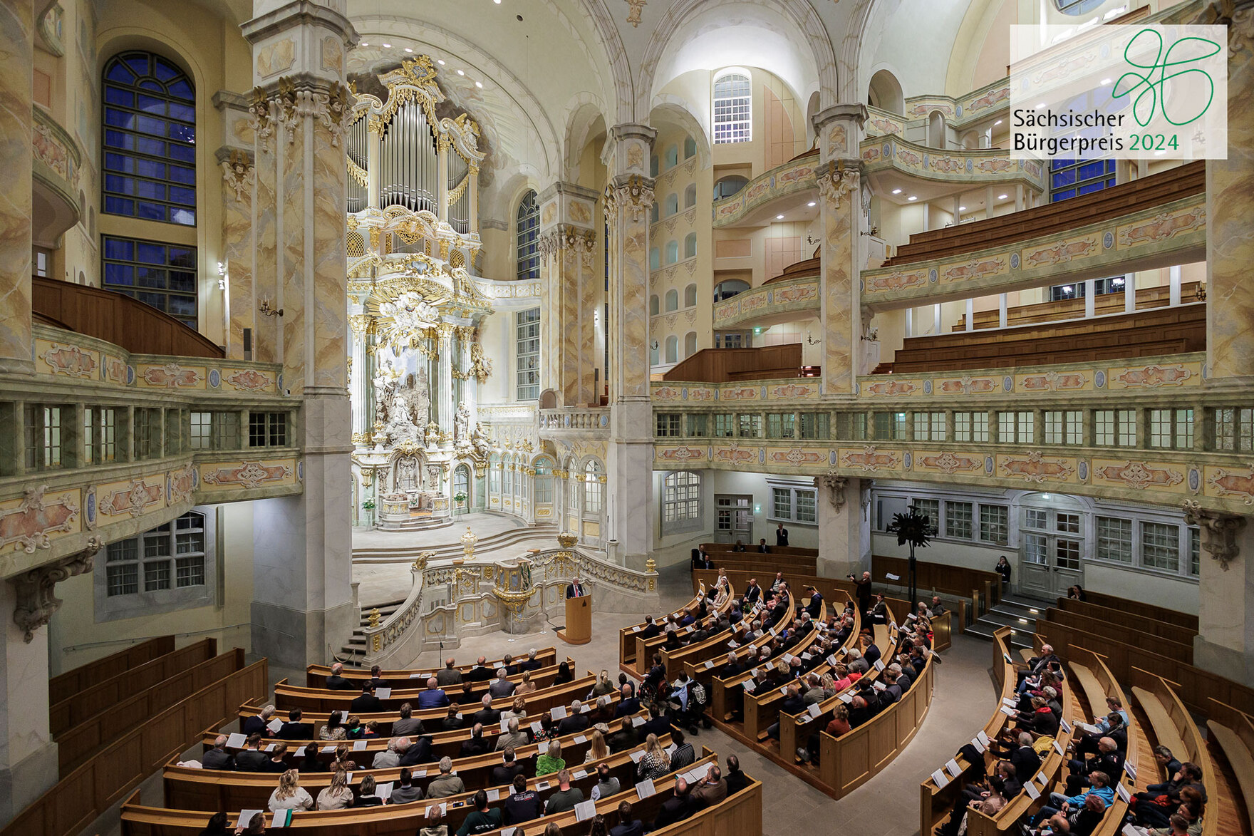 Der Blick in die mit Menschen gefüllte Dresdner Frauenkirche. Zusätzlich befindet sich auf dem Bild das Logo des Bürgerpreises 2024