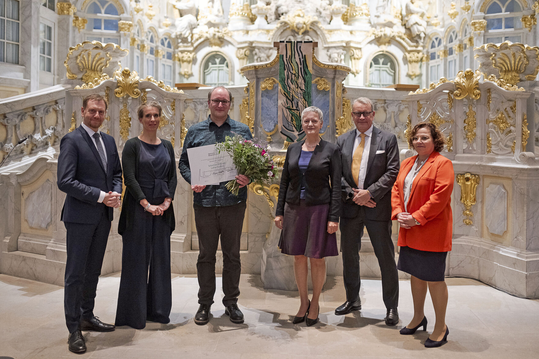 Männer und Frauen stehen vor einem Altar.