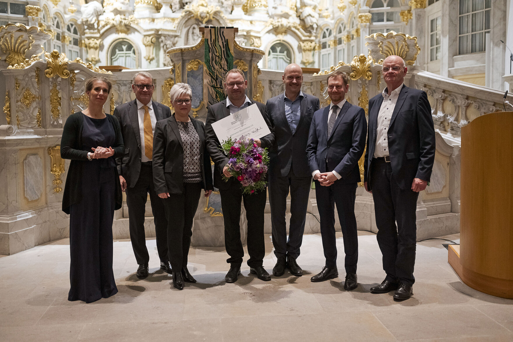 Männer und Frauen stehen vor einem Altar.